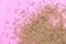 Some linseeds spread out on pink background seen from above. wooden spoon. Close up