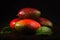 Some mango on wooded board. Black background.