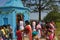 Some men and women performing puja rituals by walking round the temple and distributing sweets to the children