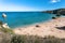 Some people lying under sun, on wide sandy beach on scenic seaside of Portugal. Ocean and bay of peaceful and sunny area