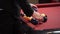 Some person wearing black clothes is racking billiards balls on red pool table.