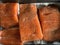 Some pieces of fillet of raw red fish with spices lie on a baking sheet before smoking, black pepper and salt, salmon