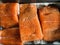 Some pieces of fillet of raw red fish with spices lie on a baking sheet before smoking, black pepper and salt, salmon