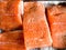 Some pieces of fillet of raw red fish with spices lie on a baking sheet before smoking, black pepper and salt, salmon