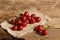 Some ripe red juicy cherries on sackcloth on an old wooden rustic bench. Harvesting. Bright sunlight.