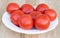 Some tomatoes in a plate on a wooden background. The benefits of tomatoes