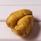 Some ugly curved potatoes on white wooden background