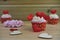 Some Valentines day romantic cup cakes with red love heart decorations on top and pink paper roses