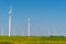 Some wind power plants in a field of flourishing rapeseed