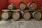 Some wooden barriques for wine aging are arranged on two levels in a Tuscan cellar