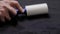 Someone is cleaning clothes with a cleaning roller, hands of a man close-up with a roller for cleaning clothes