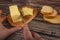 Someone cuts some butter with a knife from a piece in a wooden butter dish and fresh wheat toast on a wooden background. Close up