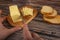 Someone cuts some butter with a knife from a piece in a wooden butter dish and fresh wheat toast on a wooden background. Close up