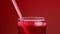 Someone drinking red soda water with ice from the glass throw the straw. Red background slow motion