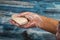 Someone is holding a piece of toilet soap on a wooden background in a soapy hand. Close up. Frequent hand washing with soap is a