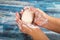 Someone is soaping their hands with a piece of toilet soap on a wooden background. Close up. Hand washing is a prevention of COVID