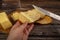 Someone spreads butter on fresh wheat toast with a knife, a wooden butter dish with butter and slices of cheese on a wooden