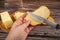 Someone spreads butter with a knife on fresh wheat toast, butter and cheese in a wooden butter dish on a wooden background. Close
