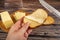 Someone spreads a little butter with a knife on fresh wheat toast, a piece of butter in a wooden butter dish, and fresh wheat