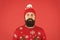 Someone stole christmas. upset because santa delay. has no present. serious hipster red background. bearded man knitted