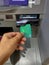 Someone takes off money from outdoor bank terminal, inserts plastic credit card in atm machine, going to withdraw money