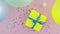 Someone throws Christmas birthday gift box wrapped in yellow paper with blue bow on pink table