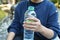 Someone wearing blue sweater holding a green plastic water bottle