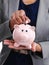 Sometimes a little goes a long way. Cropped shot of a businesswoman putting a coin into her piggybank.