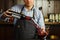 Sommelier pouring wine into glass from decanter. Male waiter