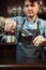 Sommelier pouring wine into glass from mixing bowl. Male waiter