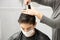 Son with facial mask while his mother cuts his hair at home