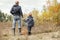 Son and father with full basket of mushrooms on the forest glade