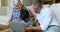 Son, father and grandfather sitting on sofa using laptop in living room