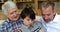 Son, father and grandfather sitting on sofa using laptop in living room