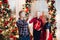 Son gives father high five while holding Christmas presents against festive decoration.