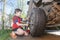 Son helps to change the wheel of the car, the boy turns a cross wrench