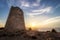 Son Jaumell watchtower at sunset with sun flare, located between Cala Agulla and Cala Mesquida, Mallorca, Spain