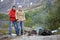 Son with mature father portrait, standing near campfire, hiking in mountains with backpacks