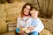 Son and mother dressed in Ukrainian embroidered shirts, sitting on hayloft, playing with live chickens in their hands