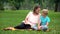 Son and mother reading interesting adventure book, sitting on blanket in park