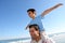 Son sitting on father\'s shoulders on the beach