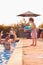 Son Squirting Father With Water Pistol Playing In Swimming Pool On Summer Vacation