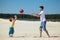 Son throws ball to father on sand