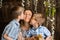 Sons kiss mom on both cheeks, hold ducklings in their hands, on  wooden background and flowering trees