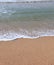 Soothing waves crashing on shore of sandy beach on a cloudy Day