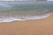 Soothing waves crashing on shore of sandy beach on a cloudy Day