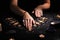 Soothsayer predicting future with tarot cards at table in darkness, closeup