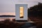 Sophisticated minimalist white tiny house by the lake at dusk, with a towering vertical window revealing a cozy interior