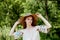 A sophisticated red-haired girl in a simple linen dress, in a light wide-brimmed hat.Model look. Natural beauty