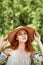 A sophisticated red-haired girl in a simple linen dress, in a light wide-brimmed hat.Model look. Natural beauty